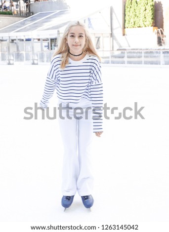 Beautiful woman skates on the ice rink in white suit.