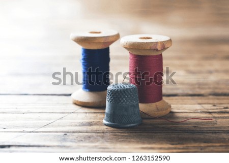 Wooden reel with thread and fingertip close-up. Selective focus. Rendered image