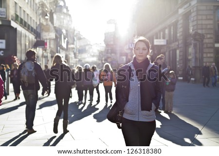 Urban girl standing out from the crowd at a city street. Royalty-Free Stock Photo #126318380
