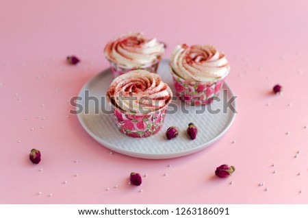 Strawberry cupcakes on white plate on pink background decorated with rosebud