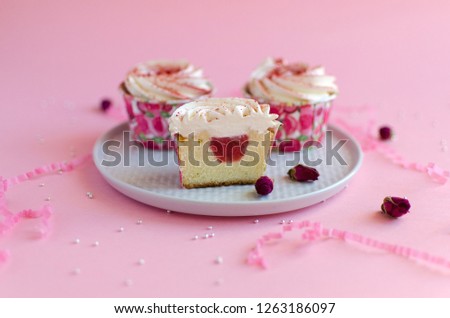 Strawberry cupcakes on white plate on pink background decorated with rosebud