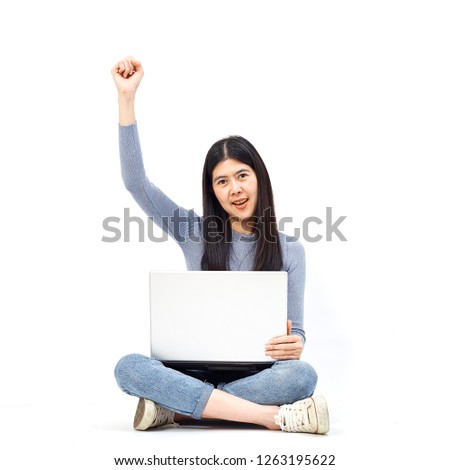 Business concept. Portrait of a smiling casual girl holding laptop computer while sitting on a floor and happy gesture on white background