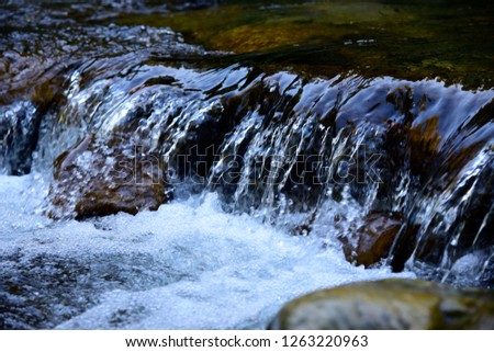 An image of a beautiful water background. Abstract landscape of the  rapids, Porcupine Mountains Wilderness. Glare and reflective surface water in river. Blue waves texture