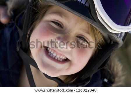 Portrait of little playful girl in ski equipment posing