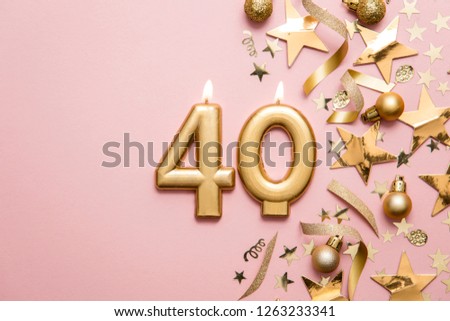 Number 40 gold celebration candle on star and glitter background
