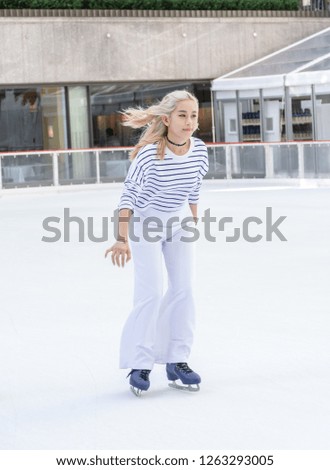 Beautiful woman skates on the ice rink in white suit.