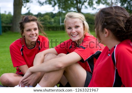 Muddy smiling teenage girls in soccer team uniform after match