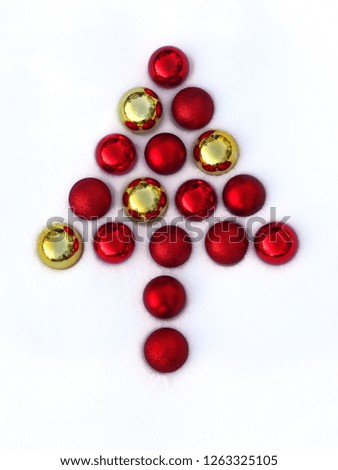 Symbolic Christmas tree made of red and gold balls on the snow.