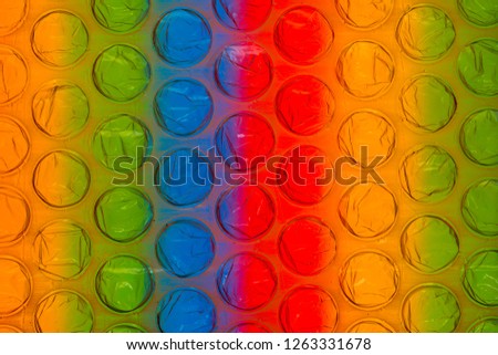 An abstract multicolored background created with a colorful image through a sheet of plastic bubble wrap