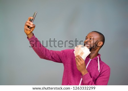 young black man smiling and holding some money taking a selfie 