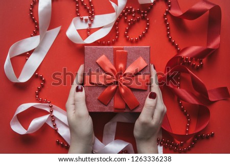 The girl is holding a red box with a gift on a festive background. Concept for Valentine's Day.