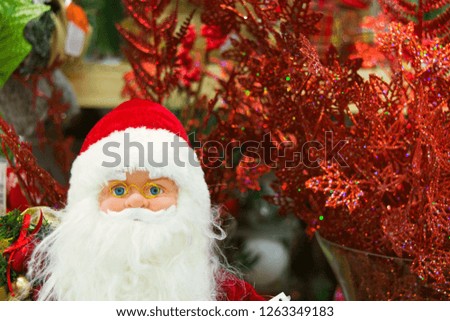 Toy Santa Claus standing in shop with New Year decoration, soft focus
