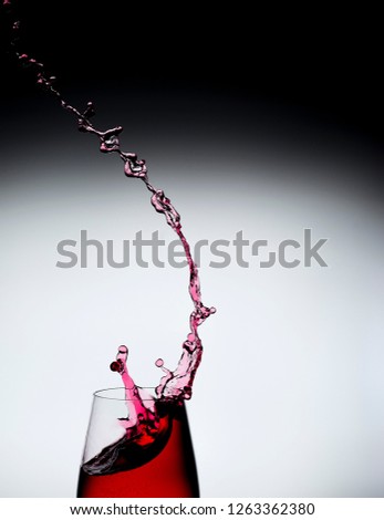 Splashed red liquid in a glass, frozen with pulsed light