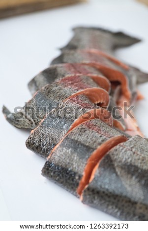 Sliced ​​large pieces of fresh red trout fish in silver skin. Cooking process. Vertical banner.