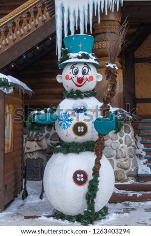 Snowman in a hat and green mittens on the background of wooden construction