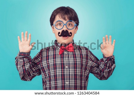 Funny boy with fake mustache and tie on blue background