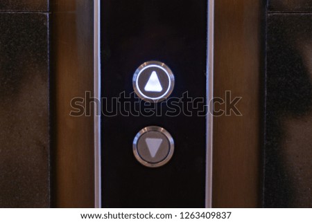 elevator call buttons on a brown wooden panel