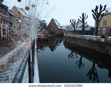 Winter at Colmar, France.
"La petite Venise" (Little Venise) canal, beautiful reflection in water, snowy roofs and street, Christmas red and silver balls in white tree. Marvelous Christmas destination