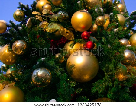 Christmas toys on fir tree closeup photo. Merry Christmas and Happy New Year postcard. Sparkling X-mas decor. Golden balls on conifer tree. Natural Christmas firtree. Lush spruce branches.