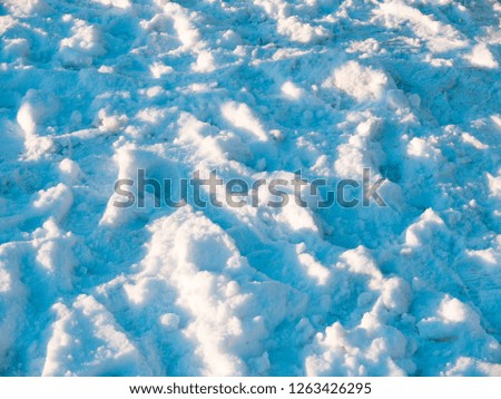 Snowdrifts on sunlight background. Blue shadows on white snow abstract photo. Merry Christmas or Happy New Year wallpaper or postcard. Frozen ground surface. Winter seasonal banner. Christmas holiday