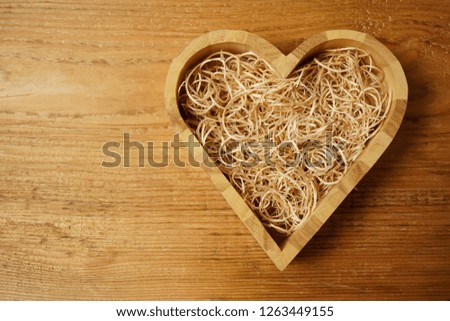 Handmade wooden heart box full with sawdust on wood  table background.   woodworking, craftsmanship and handwork concept