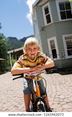 Portrait of boy at home leaning on bike in driveway