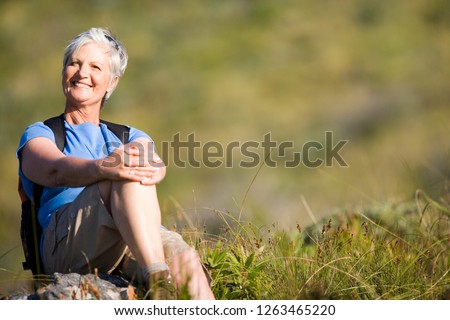 Mature woman resting on hiking along mountain trail at camera Royalty-Free Stock Photo #1263465220