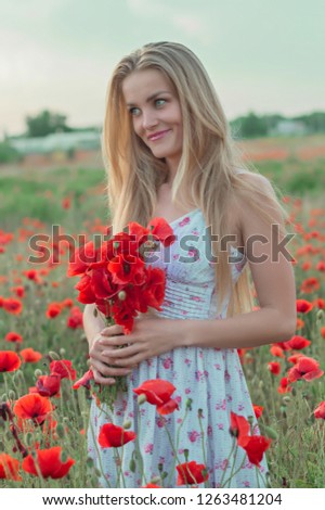 Beautiful blonde girl with long hair in the poppy field