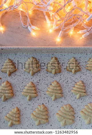 Baked Christmas sugar cookies pressed shapes on baking sheet with lights flat lay