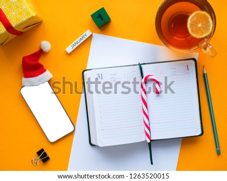 The list and goals for January 1 and the new coming year 2019. Flat lay the yellow table with a notebook, pencil, cup of tea, and a mobile phone. Planning