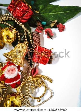 Photos about Christmas Decorated with Santa Claus red dress. And a small red gift box adorned inside the picture. There is a golden bell with green leaves on a white background.