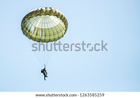 Parachutists jump from a military plane during a military exercise. Many soldiers with parachutes in the sky. Royalty-Free Stock Photo #1263585259