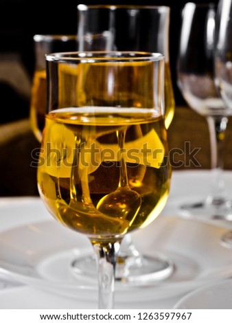 Beautiful table setting with a glass of yellow light dry table wine and champagne against the background of the dishes against the light background of the cafe, bar and restaurant.