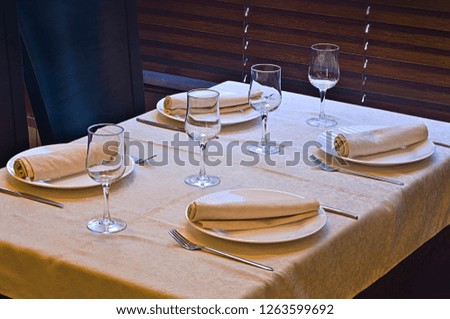 Beautiful dishes in the interior. Beautiful table setting with glasses, plates and napkins on a light background and in the interior of the cafe, bar and restaurant.