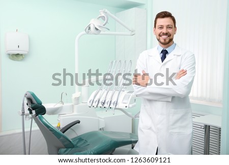 Professional male dentist in white coat at workplace. Space for text Royalty-Free Stock Photo #1263609121