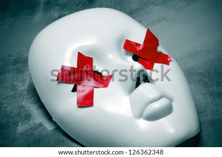 white mask with red tape strips forming crosses in its eyes on a blue background