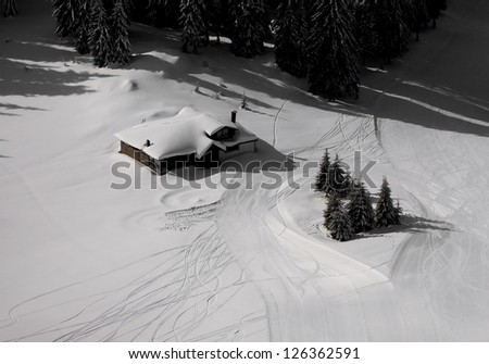 Cabin with snow and sky traces around trees in a shape of a heart. Picture is taken in Pamporovo, Bulgaria