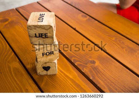 Wooden blocks with the words lie on the table. Wooden cubes with letters and symbols. Life for love.