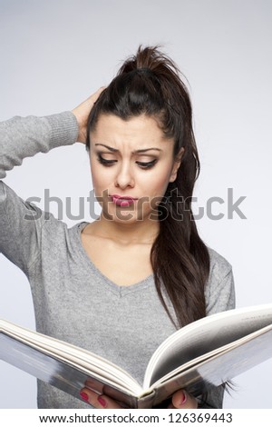 Confused young woman reading book