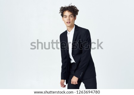 Curly young man in a classic suit bent to the side                     