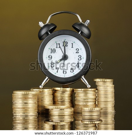 Alarm clock with coins on dark background