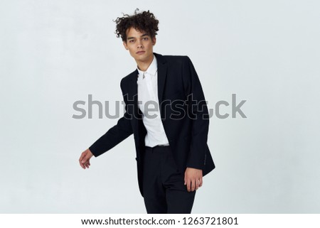 Business cute curly man in black suit on light background                  
