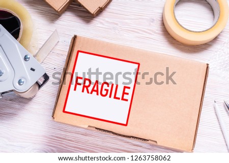 Cardboard box with fragile sticker on wooden desk, top view