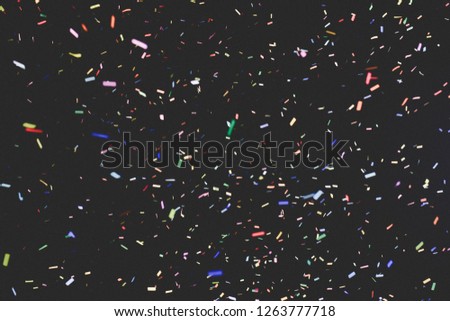Thousands of confetti fired on air during a festival at night. Image ideal for backgrounds. Multicolor are the confetti in the picture. The sky as background is black. Matt tonality