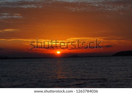 The sun is rising at the sea.The light of the sky is orange, reflected in the sea.