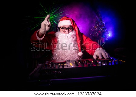 Dj Santa Claus at Christmas with glasses and snow mix on New Year's Eve event in the rays of light. Holiday club concept