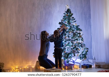 mom with son decorate Christmas tree new year gifts Garland lights