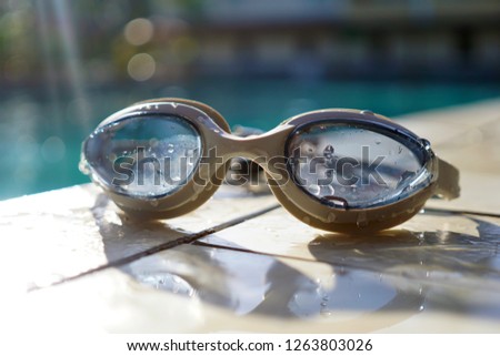 Swimming goggle at pool side on morning sunlight