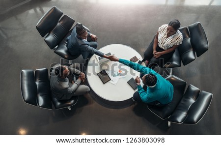 group of business people sitting and discussing statistics during a sit down meeting taking from above