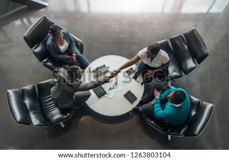 group of business people sitting and discussing statistics during a sit down meeting taking from above. Royalty-Free Stock Photo #1263803104